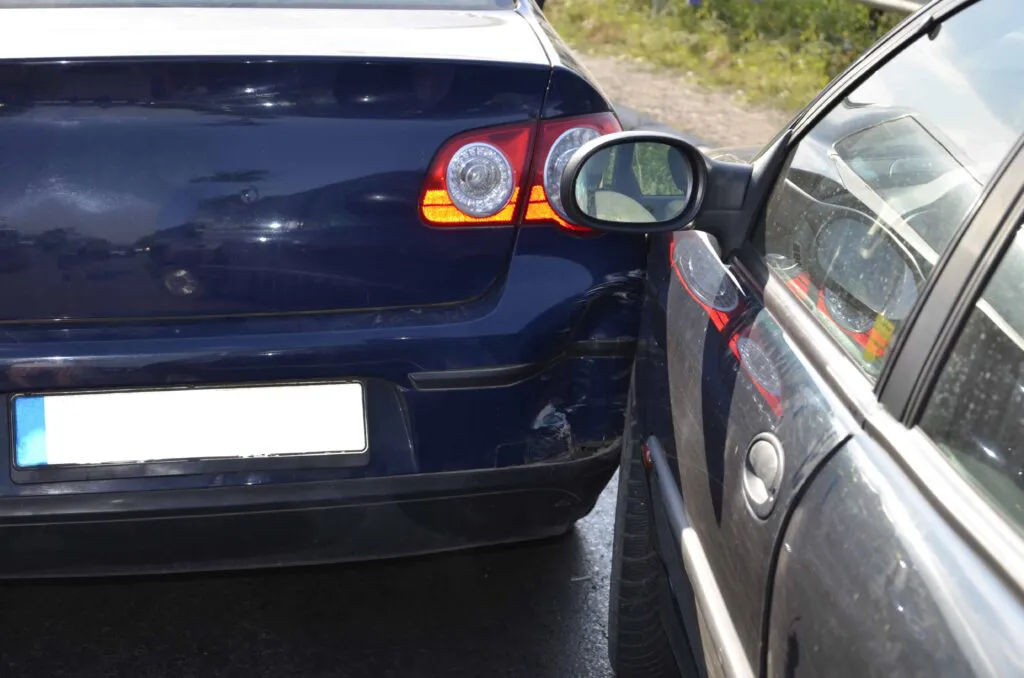Two cars involved in minor side collision on road, showing vehicle damage and car accident scene.