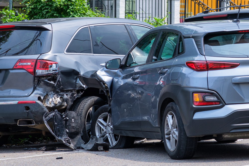 Two damaged cars after a collision on city street, representing car accident scene and vehicle crash liability.