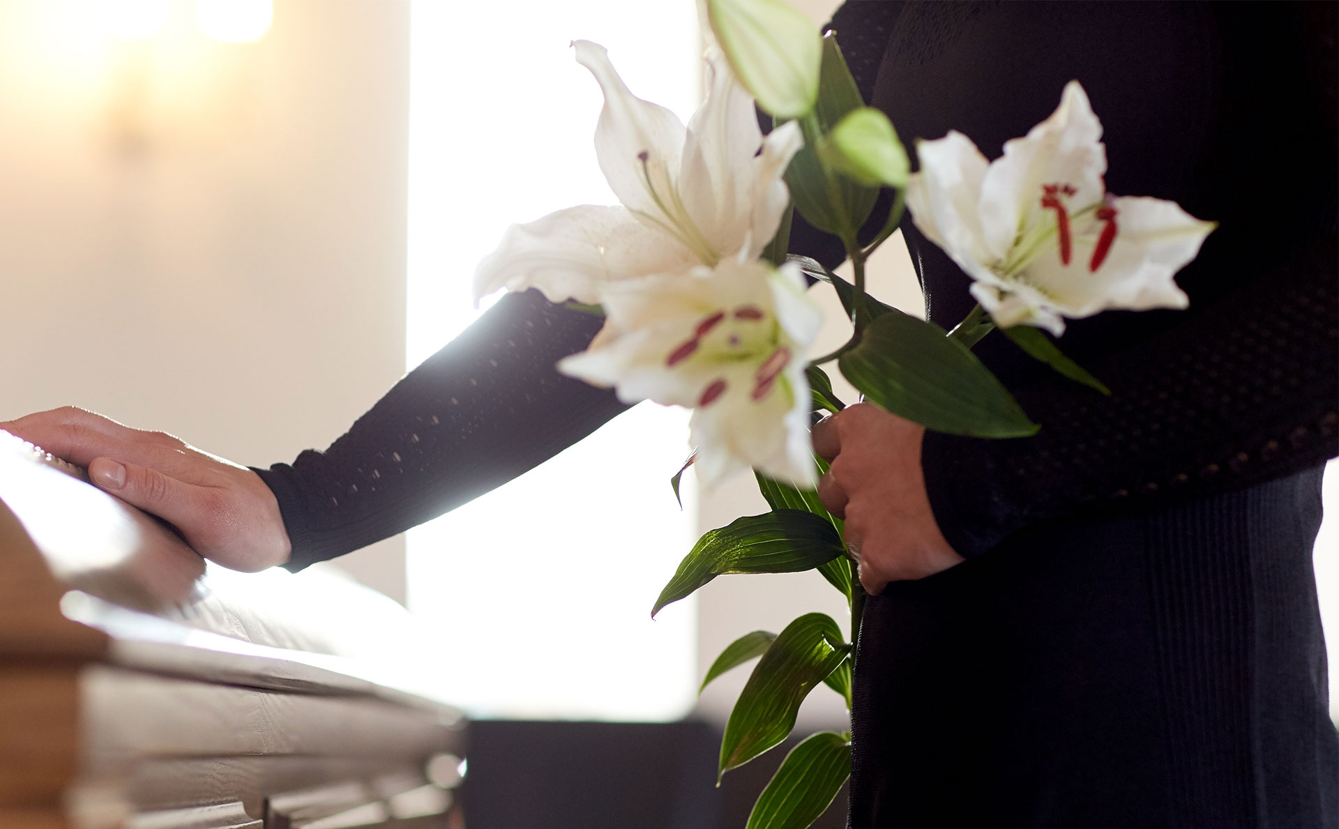 person holding flowers with hand on coffin