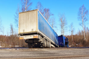 Tilted wrecked semi truck on roadside ditch
