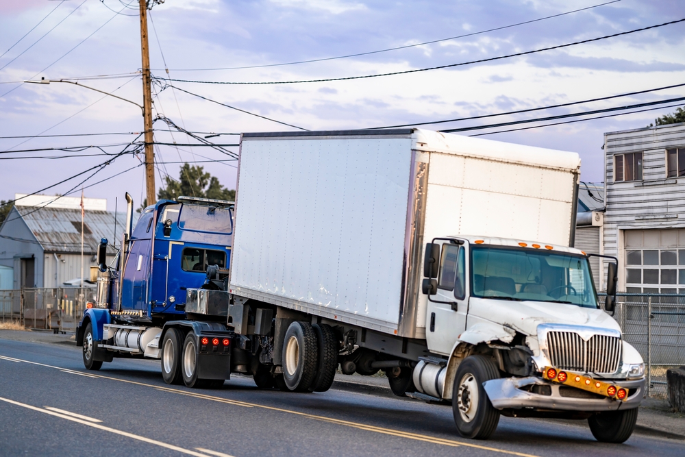Image of a large truck making a wide right turn at an intersection, illustrating potential danger to nearby vehicles.