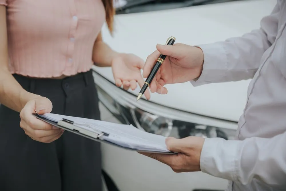 Insurance Agent examine Damaged Car and filing Report Claim Form after accident.