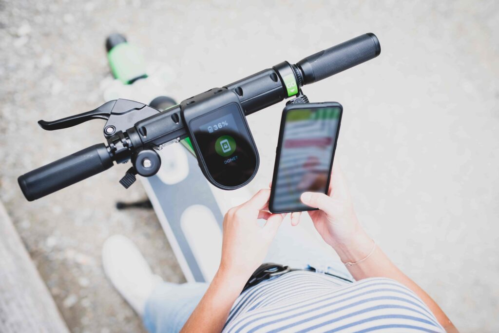 Person using smartphone to unlock or rent an electric scooter through a mobile app. Person using smartphone to unlock or rent an electric scooter through a mobile app.