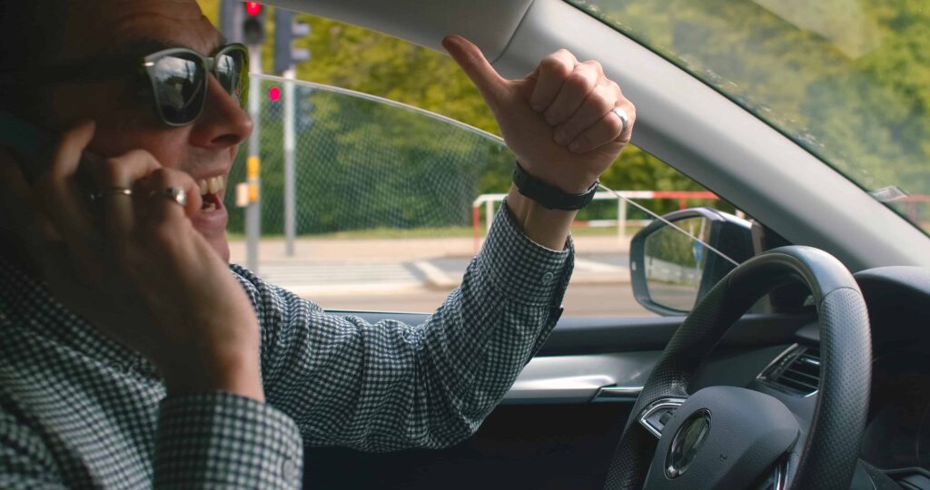 Driver talking on cellphone while driving car, representing distracted driving and traffic safety violation.