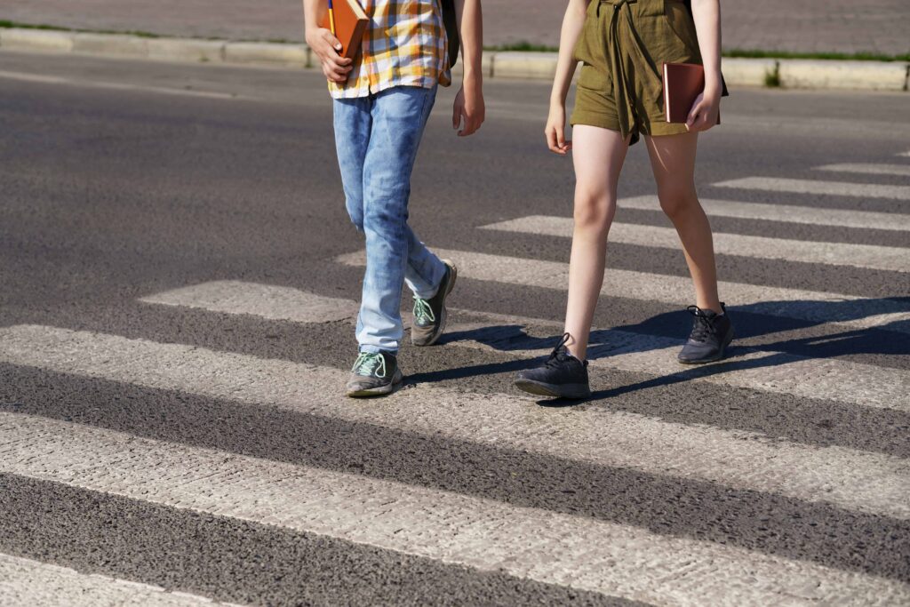 Pedestrians crossing street on crosswalk, representing pedestrian safety and right-of-way awareness.