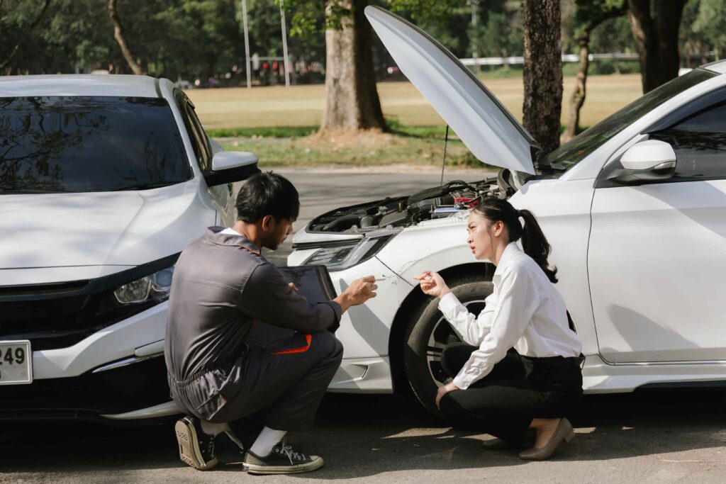 Car owner discussing damage with mechanic after accident on road, representing auto repair and insurance claim inspection.