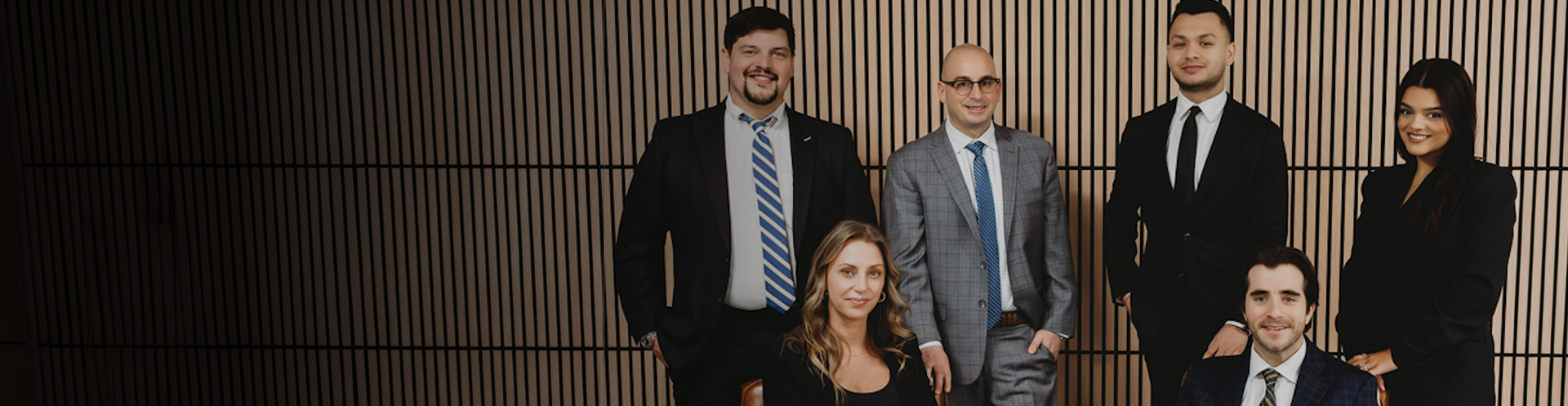 Vito & Dollenmaier Law team in front of a wood-slat wall